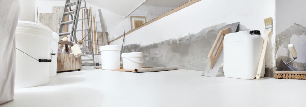 Low angle of indoor shot of construction or building site of home renovation with tools on white floor with paint buckets and primer jerry can